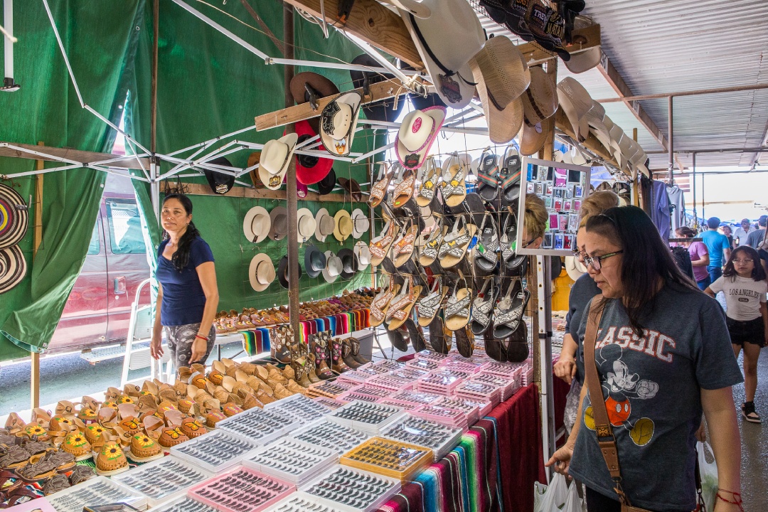 A woman gazes at a table adorned with numerous hats, highlighting the vibrant culture of the Rio Grande Valley's attractions.