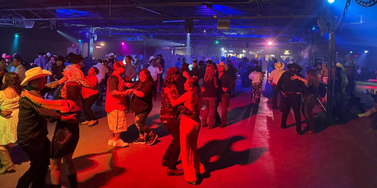 Alamo Dance Hall: A lively dance hall filled with a large group of people joyfully dancing together, showcasing the vibrant culture of the Rio Grande Valley.